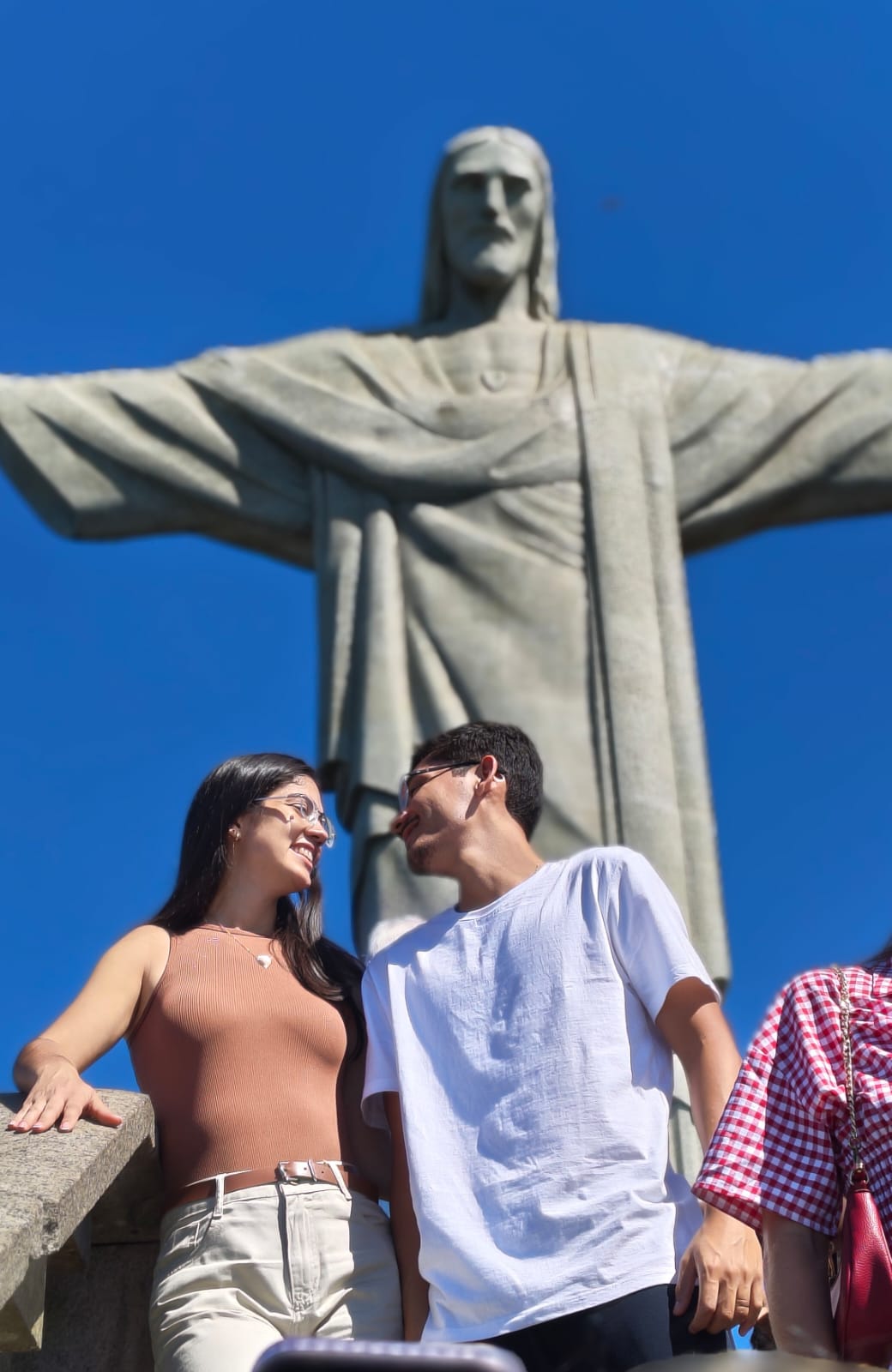 Casal sorrindo com o Cristo Redentor ao fundo